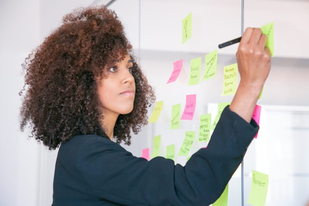 Beautiful young businesswoman writing on sticker with marker